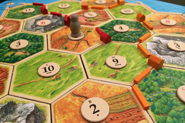 close up of settlers of catan gameboard - honeycomb shaped peices together with peices on them