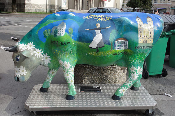 A cow statue painted with a sound of music motif.