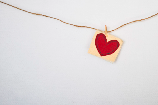 a hand drawn heart hangs from a string that stretches across the image