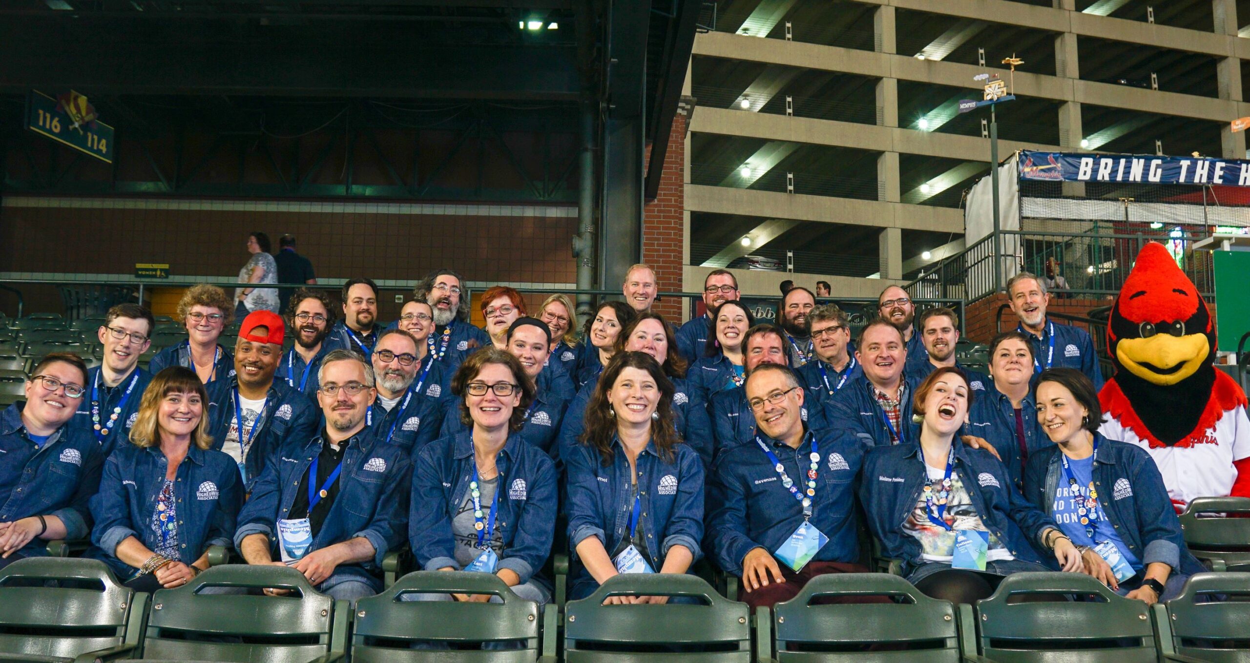 High Ed Web conference committee group photo at stadium with everyone in denim shirts