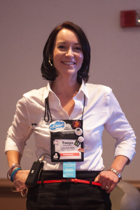 Tonya Oaks Smith smiling with conference lanyard and lots of tag swag.